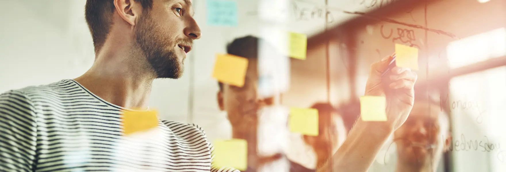 Uomo che organizza idee su una parete con note adesive durante un